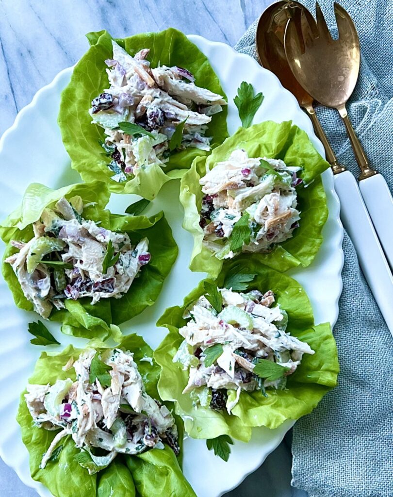 5 scoops of chicken salad on pieces of bibb lettuce. Overhead shot.