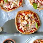 Overhead view of 3 pizzettas with red sauce, cheese and vegetables.