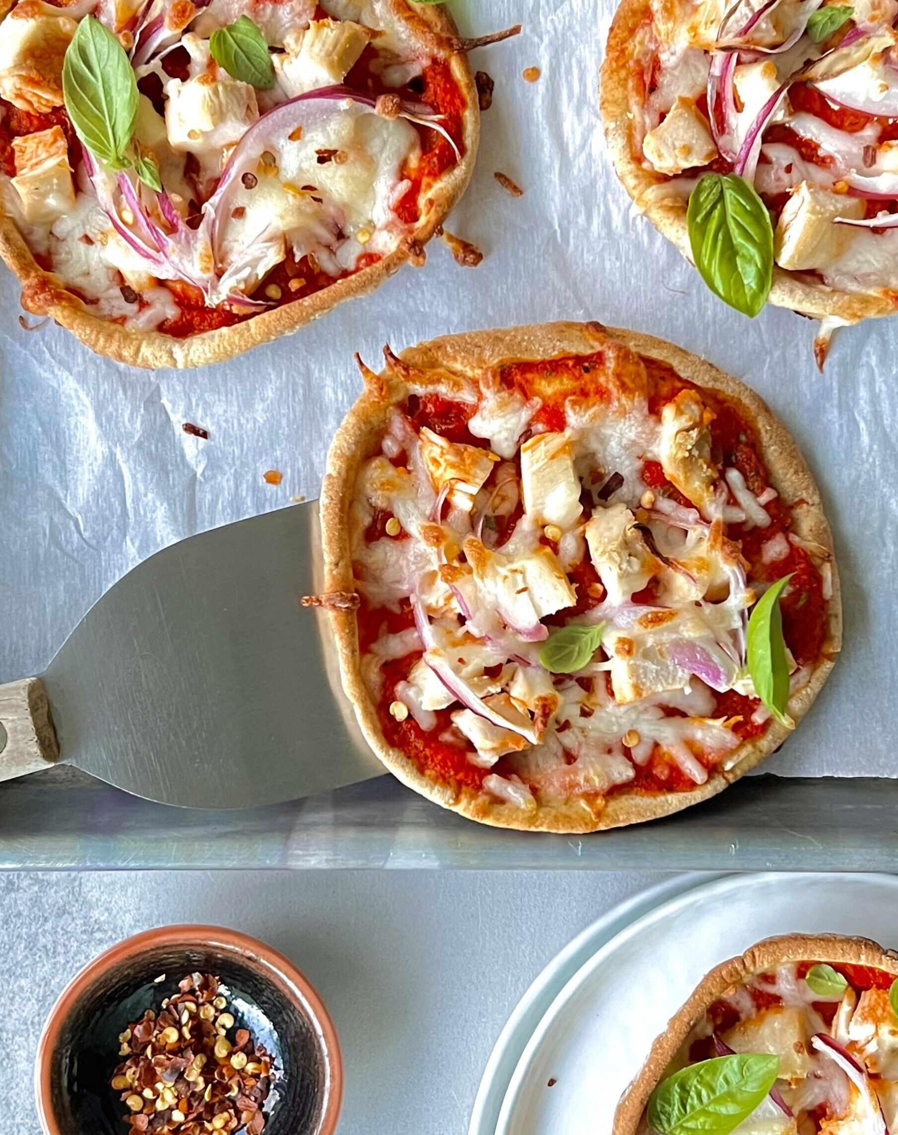 Overhead view of 3 pizzettas with red sauce, cheese and vegetables.