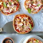 Overhead view of 3 pizzettas with red sauce, cheese and vegetables.