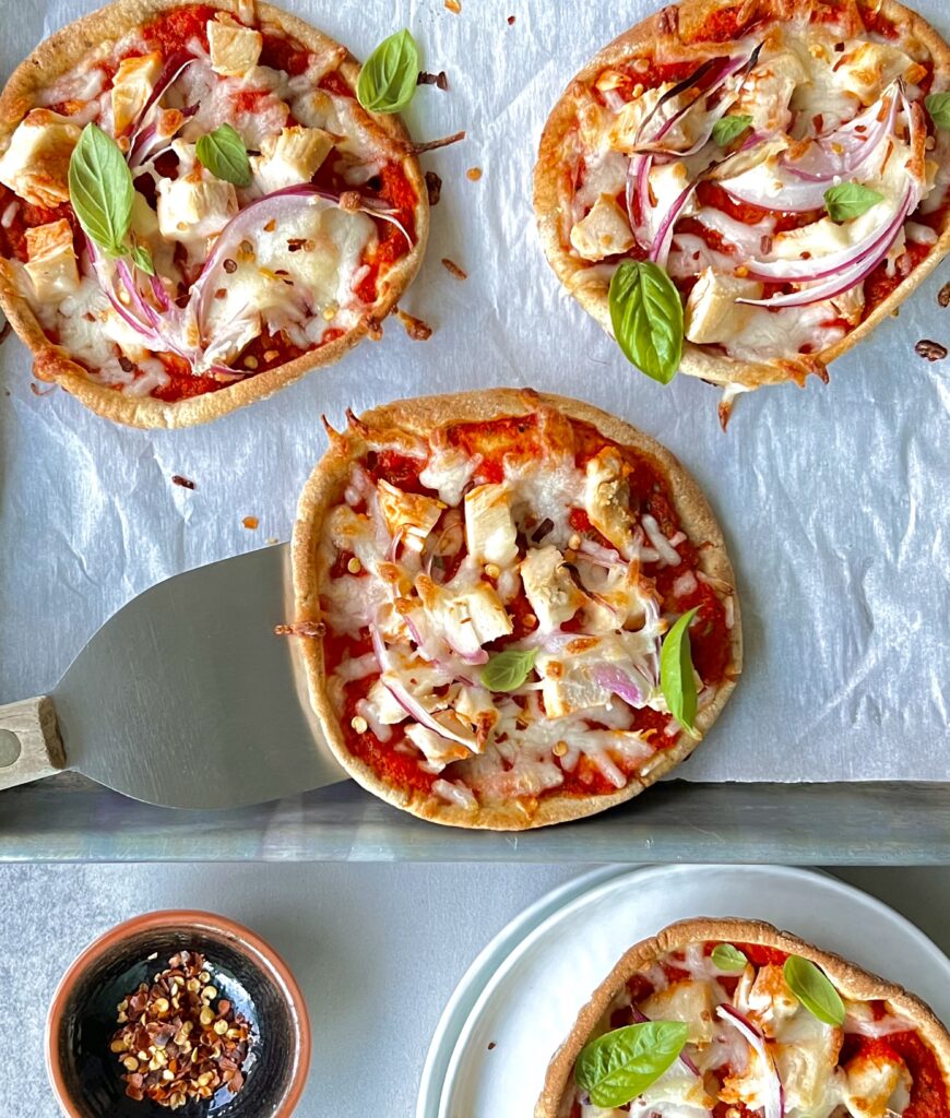 Overhead view of 3 pizzettas with red sauce, cheese and vegetables.