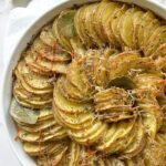 Overhead view of a baked potato gratin dish with the potatoes sliced thin, and arranged in a spiral pattern in a baking dish.