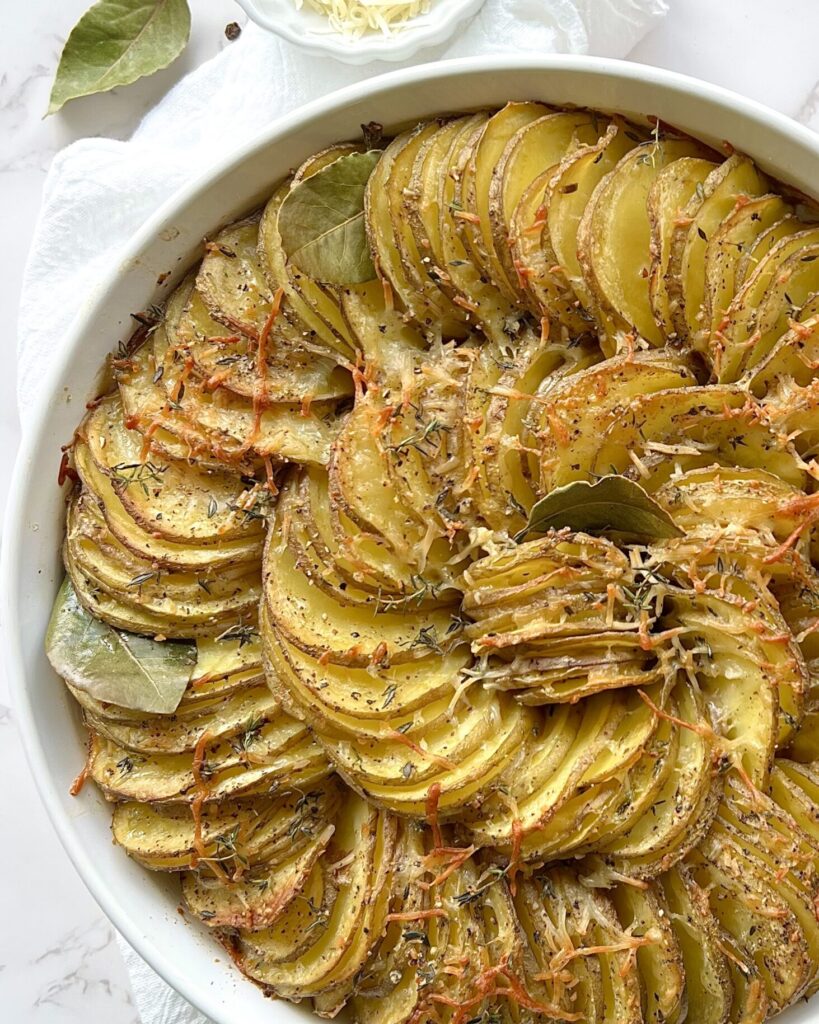 Overhead view of a baked potato gratin dish with the potatoes sliced thin, and arranged in a spiral pattern in a baking dish.