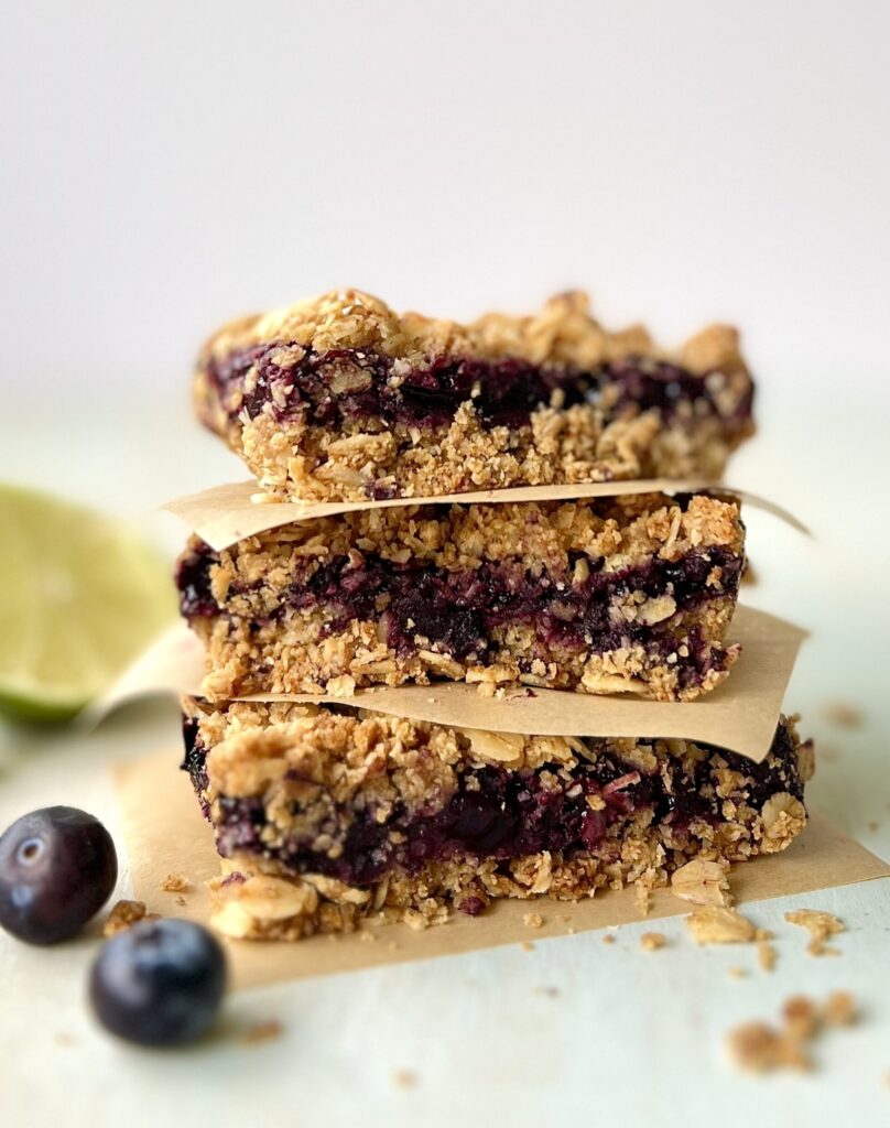 Side view of 3 blueberry oat bars stacked on top of one another with parchment paper in between.