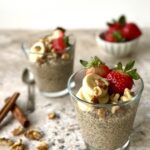 3/4 overhead view of 2 cups of the maple chia pudding topped with nuts, strawberries and banana