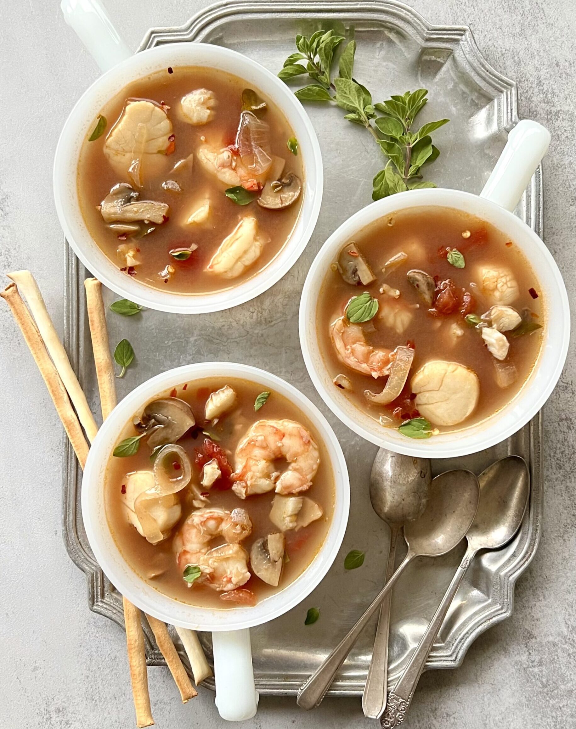 Overhead view of 3 white cups filled with seafood stew.