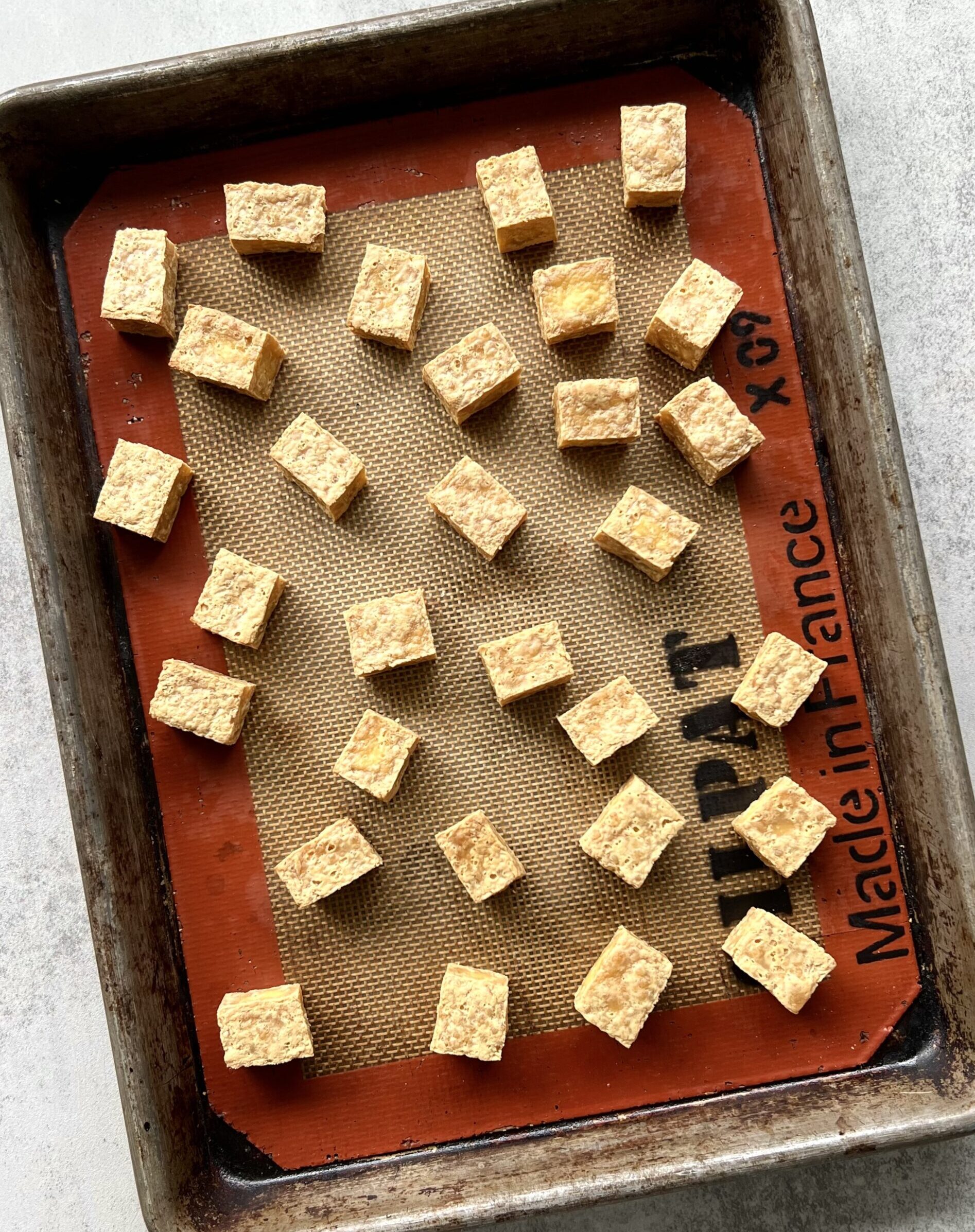 Overhead view of a baking sheet with cubes of baked tofu.